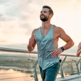 Ein Paar joggt auf einer Brücke bei Sonnenaufgang. Sie folgen einem ausgewogenen joggen und krafttraining wochenplan für ihre Fitness.
