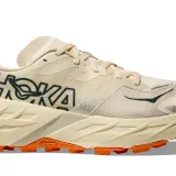 Beiger Hoka Speedgoat 7 Trailrunningschuh mit orangefarbener Vibram-Sohle und dunklem Hoka-Logo.
