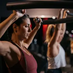 Frau trainiert Schultern im Fitnessstudio, Teil eines Bodybuilding 5er Splits.