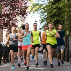Eine Gruppe von Läufern trainiert für ihren nächsten laufzeit marathon auf einer malerischen Straße mit Bäumen und Häusern.