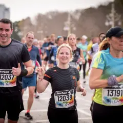 Läufer beim 10 km lauf. Ein Mann jubelt, eine Frau zeigt die Friedensgeste.