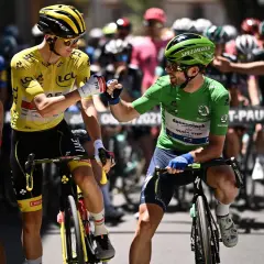 Radfahrer mit gelbem Trikot und grünen Trikot stoßen Fäuste. Ein Radfahrer im gepunkteten Trikot und einer im weißen Trikot stehen daneben. Ein Moment der Anerkennung beim Tour de France Gesamt.