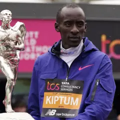 Kelvin Kiptum steht neben einer silbernen Trophäe, bereit für die Siegerehrung.