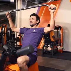 Mann trainiert im Fitnessstudio an einer Latzugmaschine. Effektives Cardio zum Abnehmen und Muskelaufbau.