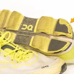 Abgenutzte Laufschuhe mit gelben Schnürsenkeln und deutlichen Abnutzungsspuren an der Sohle. Wie viele km haben diese Schuhe wohl schon hinter sich?