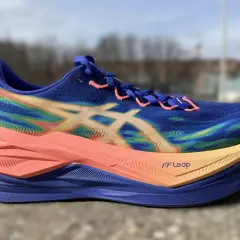 Blauer Laufschuh mit Regenbogenmuster und orangefarbener Sohle, bereit für einen superblast 3.