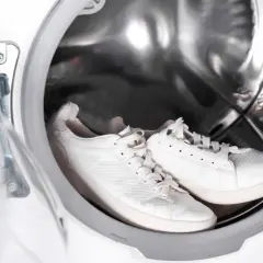 Weiße laufschuhe warten in der waschmaschine auf ihre Reinigung.