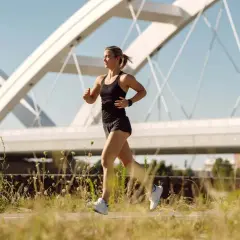 Frau joggt unter einer modernen Brücke. Sie fragt sich, wie oft joggen in der Woche gesund ist.