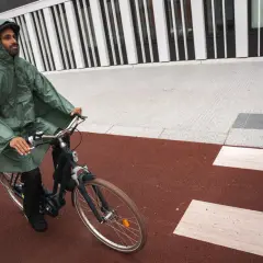 Mann mit Kapuze fährt mit einem Rennrad bei Regen.