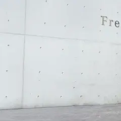 Läufer sprintet vor Betonwand mit Schriftzug "Freiburg". Bereit für den Freiburg Marathon.