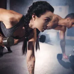 Frau und Mann trainieren im Fitnessstudio mit Hanteln. Sie konzentrieren sich auf den Muskelaufbau, aber ohne Cortison.