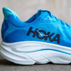 Blauer Hoka Laufschuh mit markantem Logo und dicker, weißer Sohle.