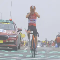 Ein Tour de France Fahrer mit Händen am Kopf, neben einem Skoda Begleitfahrzeug.