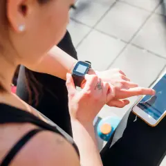 Frau prüft ihre Smartwatch und ihr Handy, um zu sehen, was ist PAI.