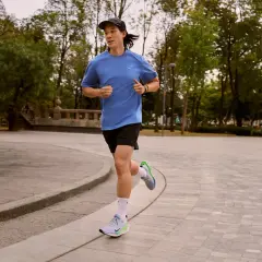 Läufer mit pronation fuss im Park, der auf einem gepflasterten Weg joggt.