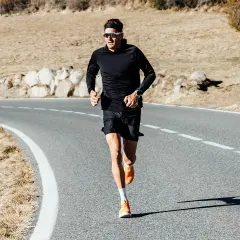 Jan Frodeno läuft auf einer Straße, seine leuchtend orangen Jan Frodeno Schuhe sind gut sichtbar.