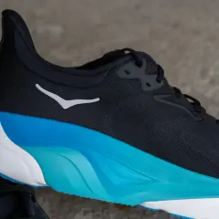 Schwarzer Hoka Arahi 8 Laufschuh mit weißem Logo und auffälliger blau-weißer Sohle.