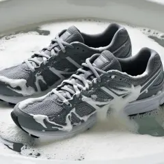 Graue Laufschuhe werden in einem Schaumbad gereinigt.