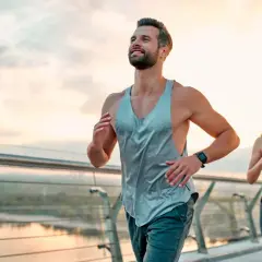 Ein Paar joggt auf einer Brücke bei Sonnenaufgang. Sie folgen einem ausgewogenen joggen und krafttraining wochenplan für ihre Fitness.
