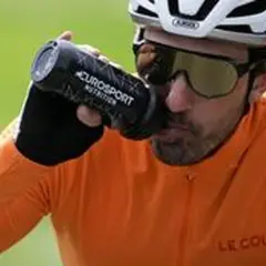 Radfahrer trinkt aus Flasche bei italienischem Radsportereignis.