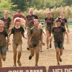 Schlammige Kinder und Erwachsene rennen lachend über eine Strecke beim xletix kids Hamburg.
