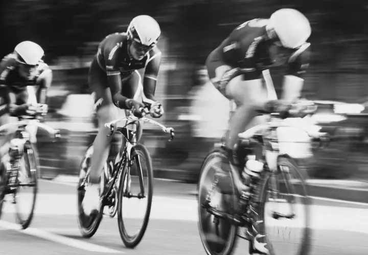 Drei Radfahrer in voller Fahrt, ein Beispiel dafür, wie funktioniert die Tour de France. Die Bewegung ist durch die Unschärfe spürbar.