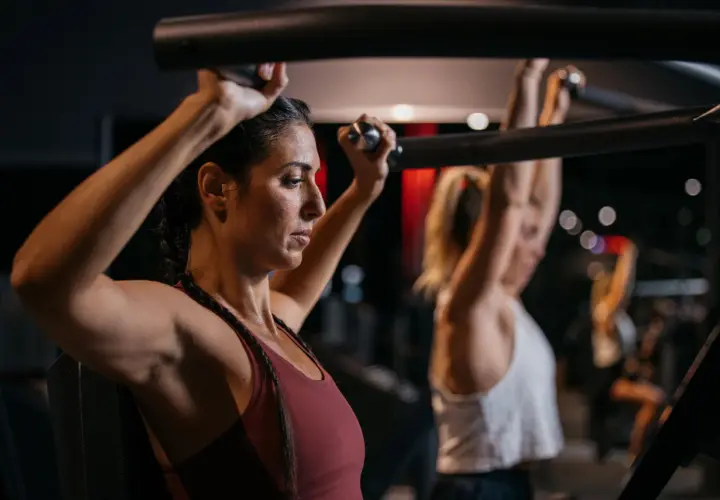 Frau trainiert Schultern im Fitnessstudio, Teil eines Bodybuilding 5er Splits.