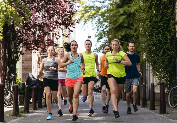 Eine Gruppe von Läufern trainiert für ihren nächsten laufzeit marathon auf einer malerischen Straße mit Bäumen und Häusern.