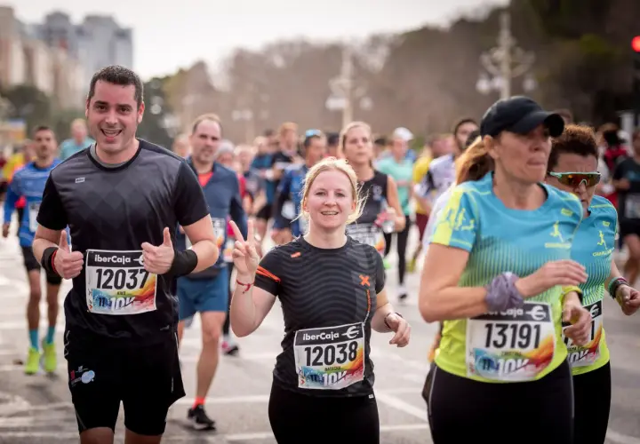 Läufer beim 10 km lauf. Ein Mann jubelt, eine Frau zeigt die Friedensgeste.