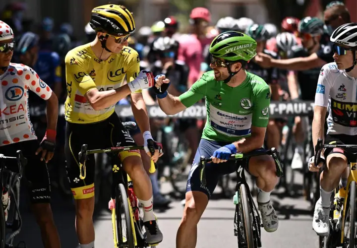 Radfahrer mit gelbem Trikot und grünen Trikot stoßen Fäuste. Ein Radfahrer im gepunkteten Trikot und einer im weißen Trikot stehen daneben. Ein Moment der Anerkennung beim Tour de France Gesamt.