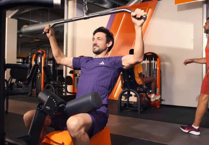 Mann trainiert im Fitnessstudio an einer Latzugmaschine. Effektives Cardio zum Abnehmen und Muskelaufbau.