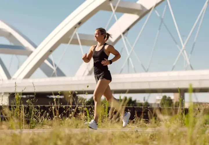 Frau joggt unter einer modernen Brücke. Sie fragt sich, wie oft joggen in der Woche gesund ist.