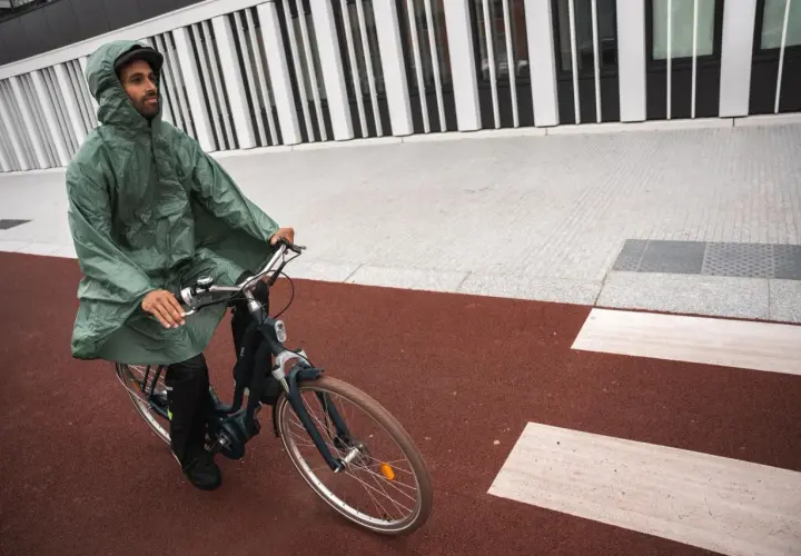 Mann mit Kapuze fährt mit einem Rennrad bei Regen.
