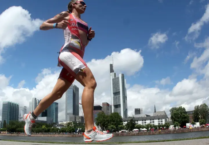 Läuferin im Triathlon-Anzug absolviert intensives Marathon-Training vor Frankfurter Skyline.