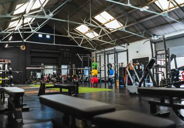 Gerät für Cardio und Muskelaufbau in einem modernen Fitnessstudio mit Hanteln, Gewichten und Trainingsbänken.