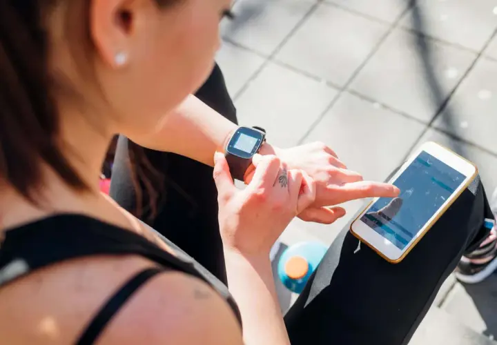Frau prüft ihre Smartwatch und ihr Handy, um zu sehen, was ist PAI.