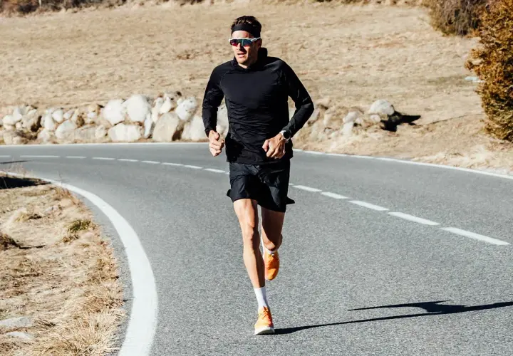 Jan Frodeno läuft auf einer Straße, seine leuchtend orangen Jan Frodeno Schuhe sind gut sichtbar.
