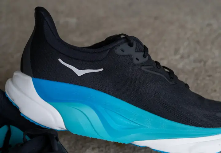 Schwarzer Hoka Arahi 8 Laufschuh mit weißem Logo und auffälliger blau-weißer Sohle.