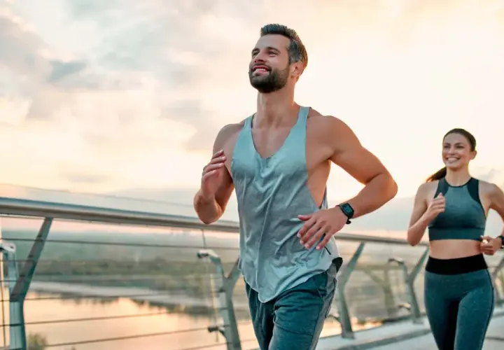 Ein Paar joggt auf einer Brücke bei Sonnenaufgang. Sie folgen einem ausgewogenen joggen und krafttraining wochenplan für ihre Fitness.