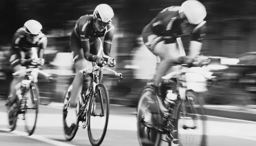 Drei Radfahrer in voller Fahrt, ein Beispiel dafür, wie funktioniert die Tour de France. Die Bewegung ist durch die Unschärfe spürbar.