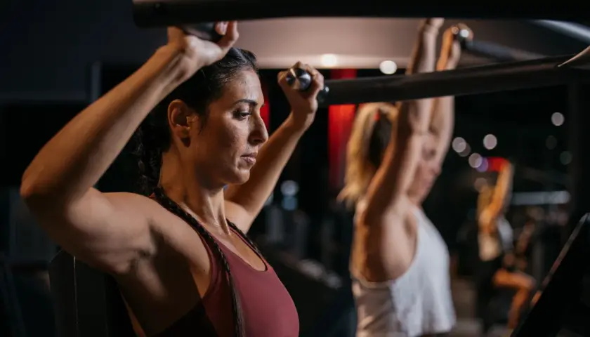 Frau trainiert Schultern im Fitnessstudio, Teil eines Bodybuilding 5er Splits.