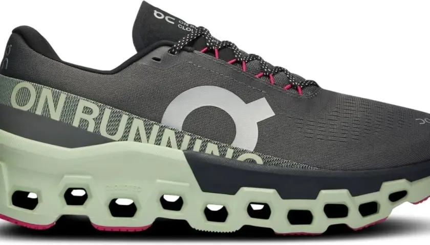 Grauer Herren-Laufschuh "Cloudmonster 2" mit hellgrüner Sohle und pinken Akzenten. "ON RUNNING" Schriftzug.
