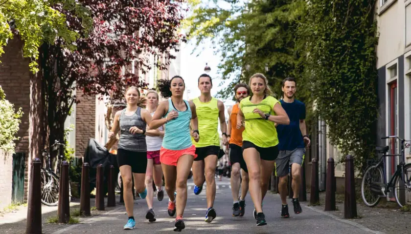 Eine Gruppe von Läufern trainiert für ihren nächsten laufzeit marathon auf einer malerischen Straße mit Bäumen und Häusern.