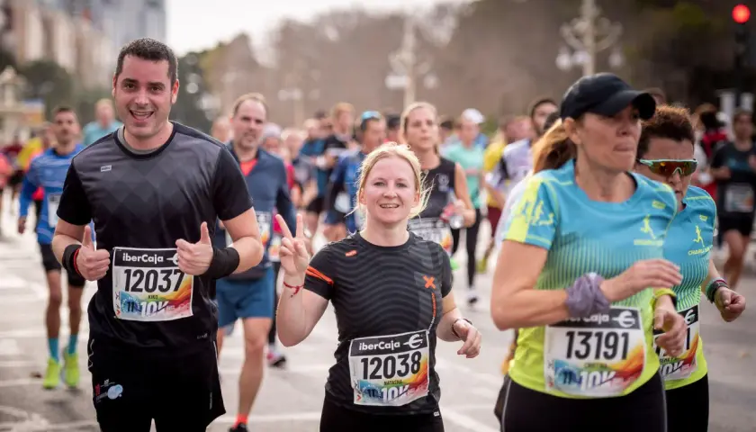 Läufer beim 10 km lauf. Ein Mann jubelt, eine Frau zeigt die Friedensgeste.