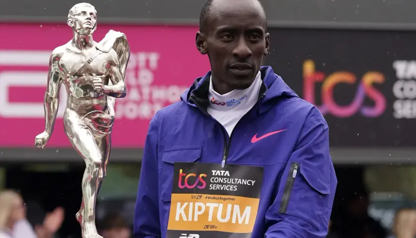 Kelvin Kiptum steht neben einer silbernen Trophäe, bereit für die Siegerehrung.