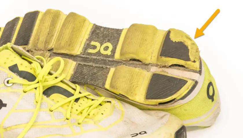 Abgenutzte Laufschuhe mit gelben Schnürsenkeln und deutlichen Abnutzungsspuren an der Sohle. Wie viele km haben diese Schuhe wohl schon hinter sich?