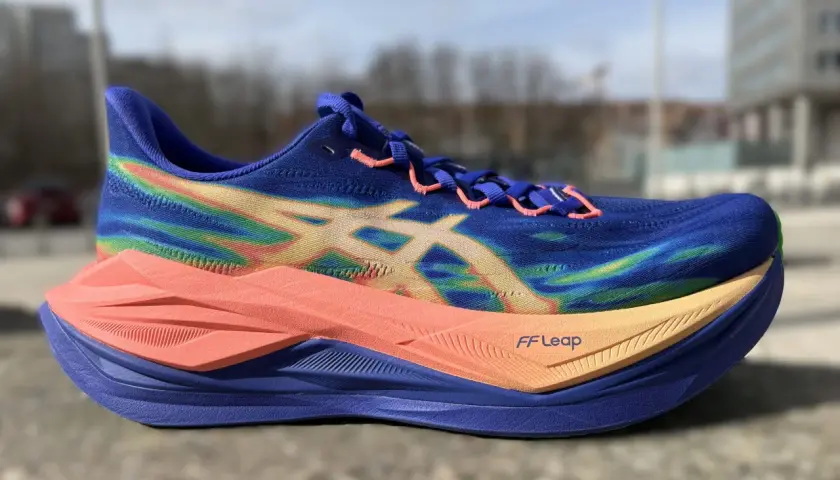 Blauer Laufschuh mit Regenbogenmuster und orangefarbener Sohle, bereit für einen superblast 3.
