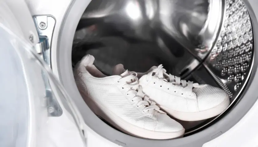 Weiße laufschuhe warten in der waschmaschine auf ihre Reinigung.