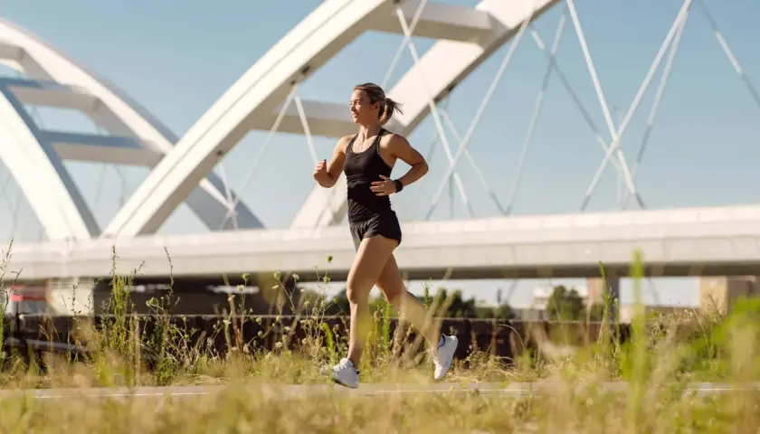 Frau joggt unter einer modernen Brücke. Sie fragt sich, wie oft joggen in der Woche gesund ist.
