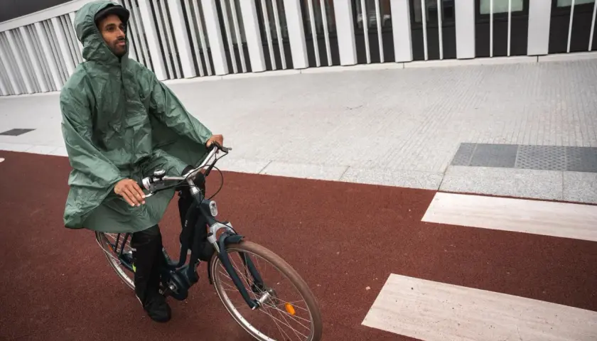 Mann mit Kapuze fährt mit einem Rennrad bei Regen.